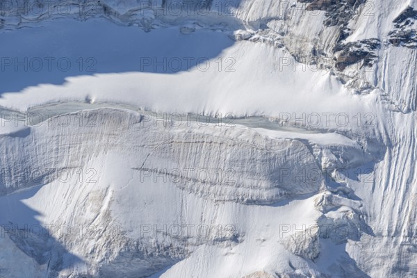 A large blanket of snow covers the rocks in the mountains. The sky is clear and reflects the serene beauty of the Alps. The snow looks fresh and immaculate. Gorner Glacier, Zermatt, Valais, Alps, Swiss