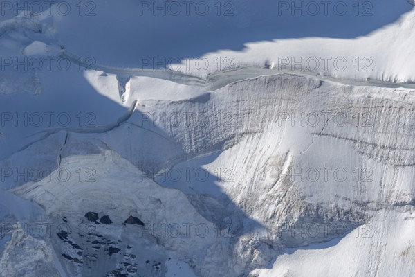 A large blanket of snow covers the rocks in the mountains. The sky is clear and reflects the serene beauty of the Alps. The snow looks fresh and immaculate. Gorner Glacier, Zermatt, Valais, Alps, Swiss