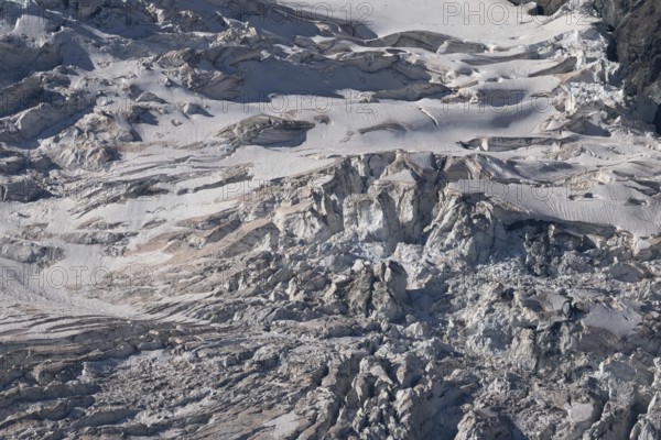 A spectacular glacier unfolds in the light, revealing its crevasses and layers of ice in a mountainous region. Shades of grey underline the beauty of the glacier formations. Gorner Glacier, Zermatt, Valais, Alps, Swiss