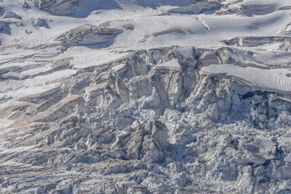 A spectacular glacier unfolds in the light, revealing its crevasses and layers of ice in a mountainous region. Shades of grey underline the beauty of the glacier formations. Gorner Glacier, Zermatt, Valais, Alps, Swiss