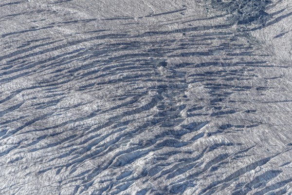 Crevices mark the surface of the glacier. The landscape is illuminated by daylight, highlighting the structure and colour of the ice. Gorner Glacier, Zermatt, Valais, Alps, Swiss