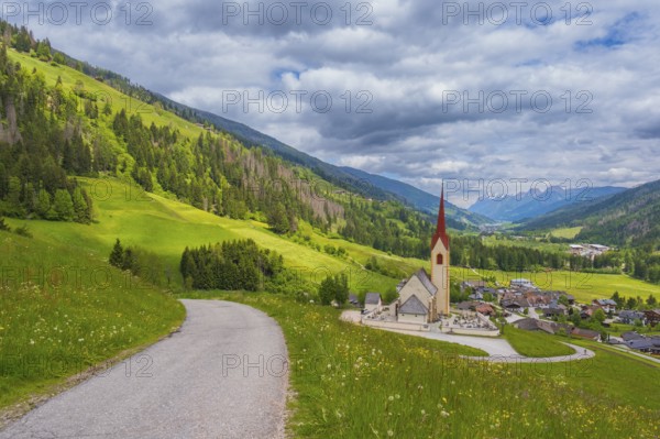 View along a road to the church of Winnebach with the valley behind it, San Candido, Val Pusteria, Dolomites, South Tyrol, Italy