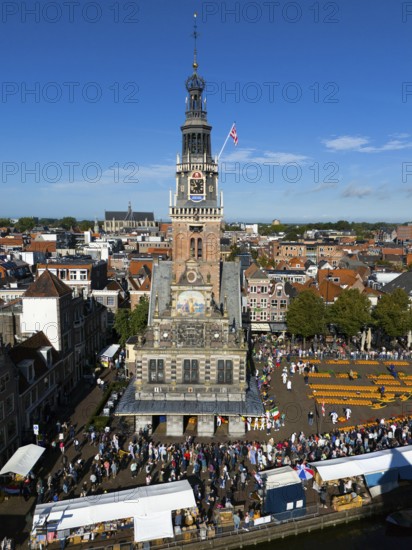 Imposing clock tower with lively market activity and market stalls in the foreground, under blue sky, aerial view, cheese, cheese market, former city scales, Alkmaar, Alkmar, Noord-Holland, North-Holland, Netherlands