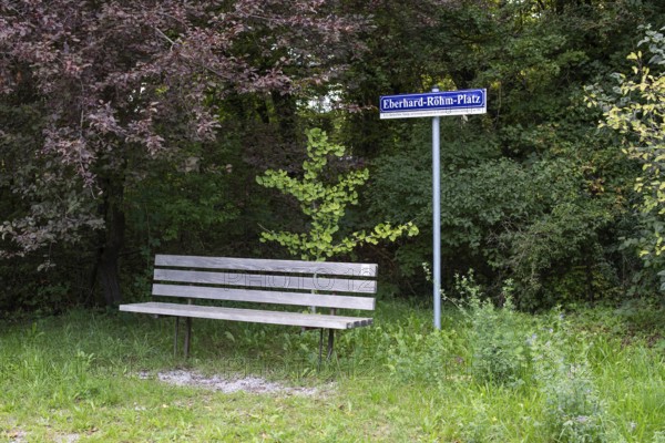 Wooden bench in front of a sign with the inscription Eberhard-Röhm-Platz, square named after a founding member of the Leonberg Concentration Camp Memorial, Leonberg, Baden-Württemberg