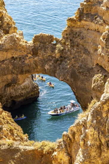 Crowds of excursion boats at the caves and rocky gates of the Ponta da Piedade rocky coast, rugged coastal landscape, right by the centre of Lagos, in the west of the Algarve, Portugal