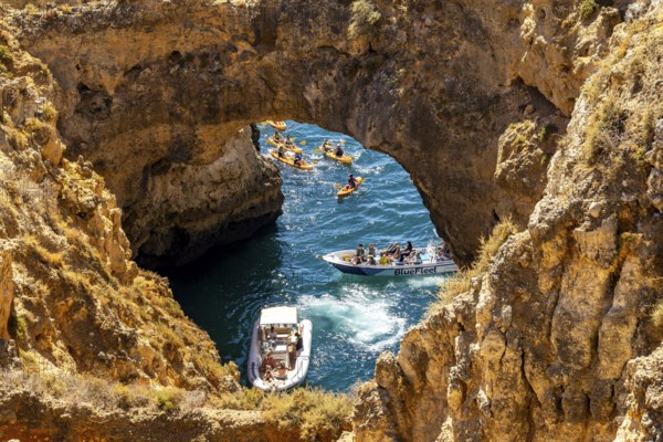 Crowds of excursion boats at the caves and rocky gates of the Ponta da Piedade rocky coast, rugged coastal landscape, right by the centre of Lagos, in the west of the Algarve, Portugal