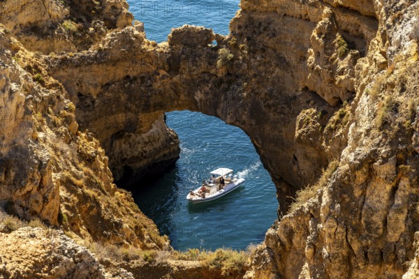 Excursion boats at the caves and rocky gates of the Ponta da Piedade rocky coast, rugged coastal landscape, right by the centre of Lagos, in the west of the Algarve, Portugal