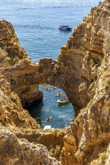 Crowds of excursion boats at the caves and rocky gates of the Ponta da Piedade rocky coast, rugged coastal landscape, right by the centre of Lagos, in the west of the Algarve, Portugal