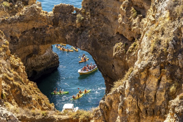 Crowds of excursion boats at the caves and rocky gates of the Ponta da Piedade rocky coast, rugged coastal landscape, right by the centre of Lagos, in the west of the Algarve, Portugal