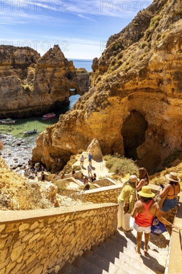 Tourists at the caves and rocky gates of the Ponta da Piedade rocky coast, rugged coastal landscape, right next to the city centre of Lagos, in the west of the Algarve, Portugal