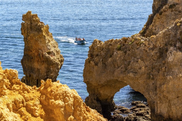 Excursion boats at the caves and rocky gates of the Ponta da Piedade rocky coast, rugged coastal landscape, right by the centre of Lagos, in the west of the Algarve, Portugal