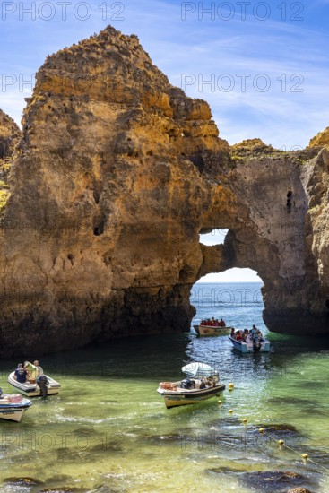 Excursion boats at the caves and rocky gates of the Ponta da Piedade rocky coast, rugged coastal landscape, right by the centre of Lagos, in the west of the Algarve, Portugal