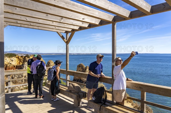 Tourists on the rocky coast of Ponta da Piedade, rugged coastal landscape, right next to Lagos city centre, in the west of the Algarve, Portugal