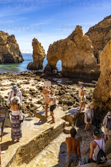 Tourists at the caves and rocky gates of the Ponta da Piedade rocky coast, rugged coastal landscape, right next to the city centre of Lagos, in the west of the Algarve, Portugal