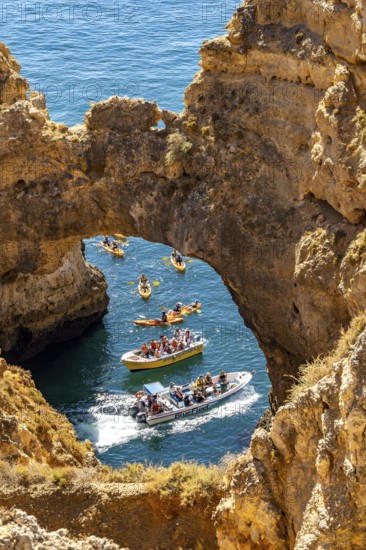 Crowds of excursion boats at the caves and rocky gates of the Ponta da Piedade rocky coast, rugged coastal landscape, right by the centre of Lagos, in the west of the Algarve, Portugal