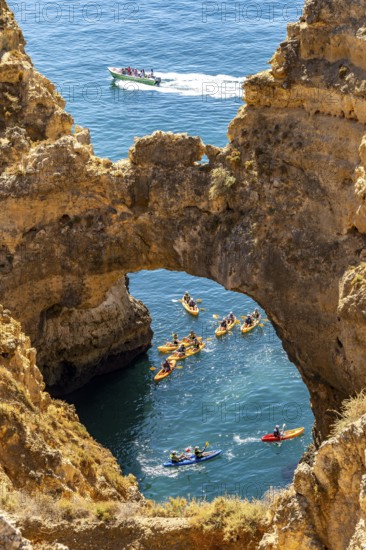 Crowds of excursion boats at the caves and rocky gates of the Ponta da Piedade rocky coast, rugged coastal landscape, right by the centre of Lagos, in the west of the Algarve, Portugal