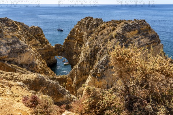 Crowds of excursion boats at the caves and rocky gates of the Ponta da Piedade rocky coast, rugged coastal landscape, right by the centre of Lagos, in the west of the Algarve, Portugal