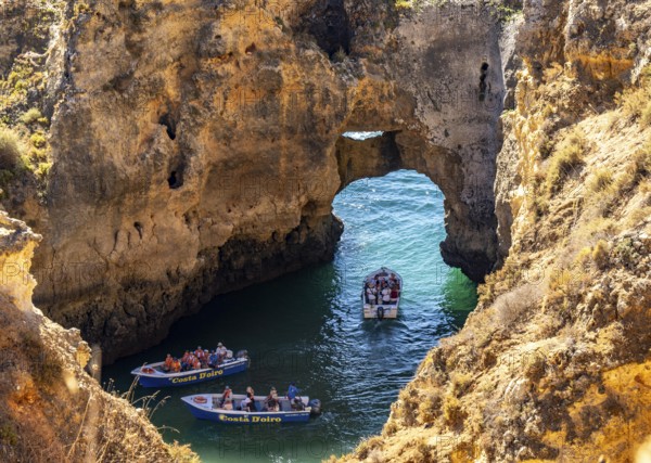 Excursion boats at the caves and rocky gates of the Ponta da Piedade rocky coast, rugged coastal landscape, right by the centre of Lagos, in the west of the Algarve, Portugal