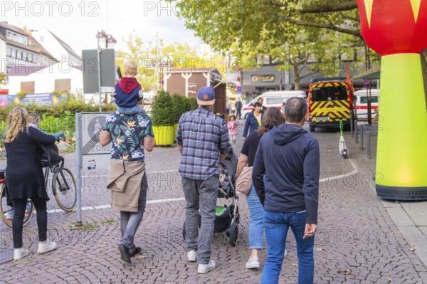 Group of people strolling through town with prams and children on their shoulders, Sindelfingen, Böblingen district, Germany