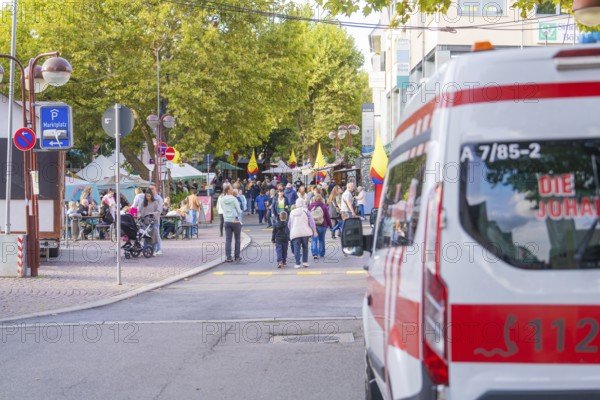 An ambulance parked near a busy market square with a crowd of people, Sindelfingen, Böblingen district, Germany