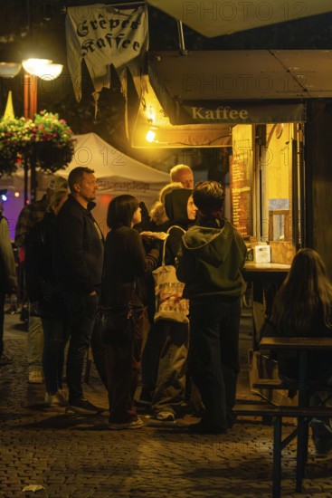 People standing at night at an illuminated food stall in a park, Sindelfingen, Böblingen district, Germany