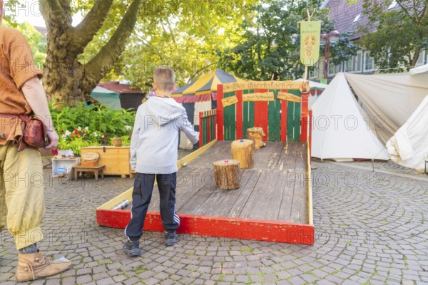 A child plays a medieval wooden game on a market square, Sindelfingen, Böblingen district, Germany