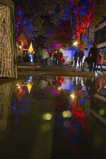 Colourful night lights reflected in a rain-soaked street during an event, Sindelfingen, Böblingen district, Germany