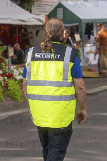 Person in yellow safety waistcoat on a market square, Sindelfingen, Böblingen district, Germany