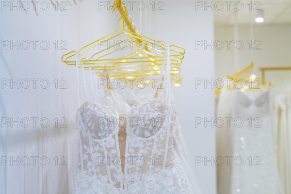 Row of white wedding dresses made of filigree lace presented on yellow hangers, Sindelfingen, Böblingen district, Germany