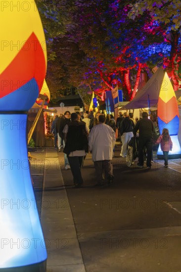 People walking at night on a street illuminated with colourful lights, Sindelfingen, Böblingen district, Germany