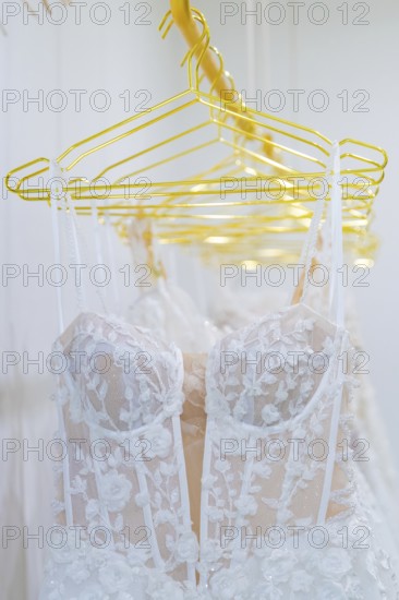 White lace wedding dresses hang elegantly on yellow hangers, Sindelfingen, Böblingen district, Germany