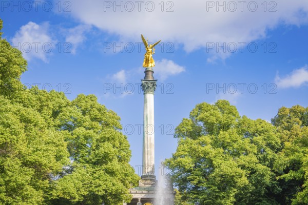 A golden statue rises on a column surrounded by trees, Munich, Germany