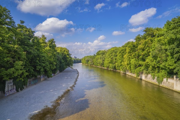 A river flows between lush green trees under a clear sky, Munich, Germany