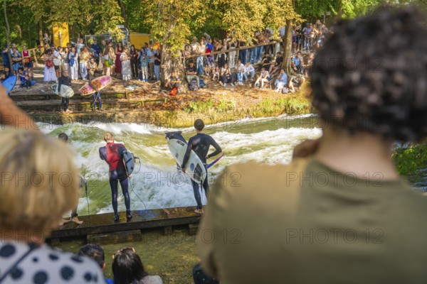 Surfers prepare for water riding on the river bank while spectators watch, Munich, Germany