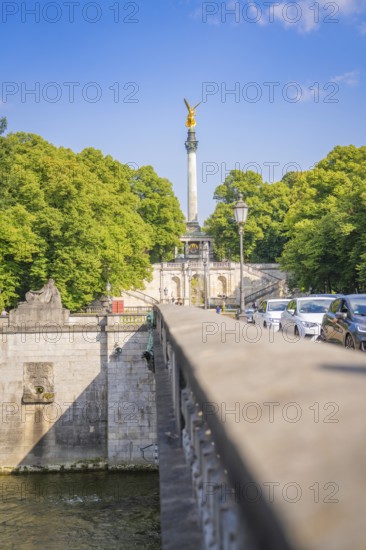 Urban view with bridge and traffic cars, surrounded by tall green trees and blue sky, Munich, Germany