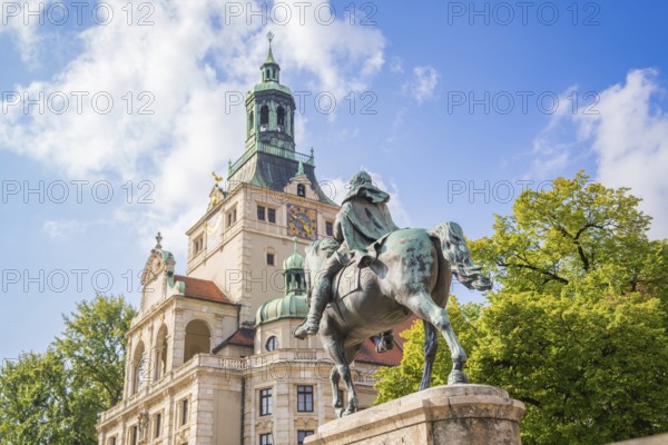 Equestrian statue in front of a magnificent historical building, surrounded by trees and blue sky, Munich, Germany