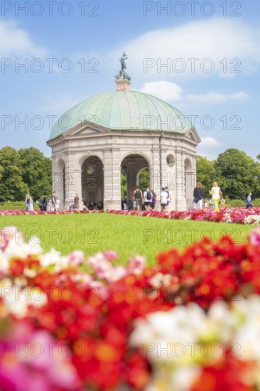 Flowery pavilion with green dome in front of a colourful flower bed and under a blue sky, Munich, Germany