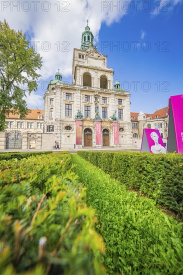Impressive historic building with towers and a well-tended green space under a blue sky, Munich, Germany