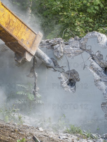 Close-up of a demolition hammer smashing concrete, surrounded by dust and plants, bridge demolition, Calw, Germany