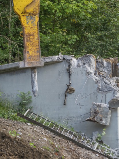 A demolition hammer destroys concrete, a ladder leans against the wall, surrounded by plants, bridge demolition, Calw, Germany