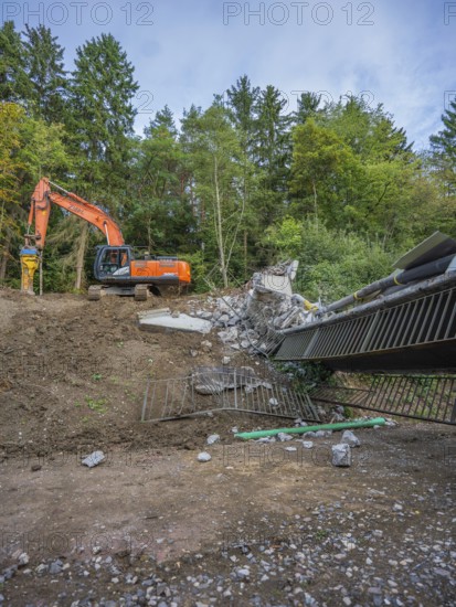 An excavator is demolishing a bridge in a wooded area, bridge demolition, Calw, Germany