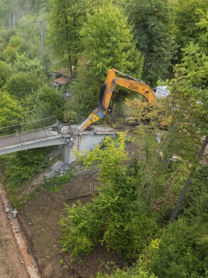 An excavator works on the demolition of a bridge from above in a forest area, bridge demolition, Calw, Germany