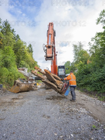 A worker uses an excavator to carry out work on tree trunks on ballast, bridge demolition, Calw, Germany