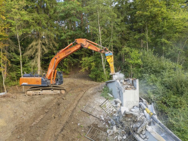 An excavator demolishes a wooden bridge in a wooded area, bridge demolition, Calw, Germany