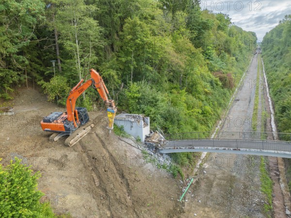 An excavator demolishes a bridge next to railway tracks in the forest, bridge demolition, Calw, Germany