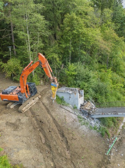 An excavator works on the dismantling of a bridge in a wooded area, bridge demolition, Calw, Germany