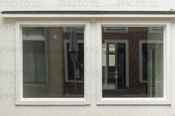 TBorken, NRW, Germany, wo large windows are reflecting a brick building and a parasol on a white wall