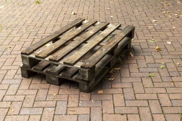 Borken, NRW, Germany, Two weathered wooden pallets are placed on a herringbone brick pavement, showing signs of wear and tear