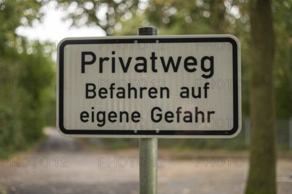 Borken, NRW, Germany, German warning sign privatweg befahren auf eigene gefahr on a pole in a forest path