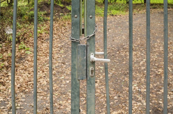 Borken, NRW, Germany, Old metal gate closed with a chain and handle, blocking a path in the forest